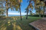 This stunning lakeside property boasts a spacious lawn, mature trees providing shade, and a brick patio perfect for outdoor entertaining.
