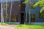 This stunning modern home boasts a unique blend of dark wood and sleek metal siding, creating a striking contrast.