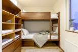 Cozy bunk bed room with built-in wooden shelves and drawers, perfect for storing luggage and personal items.