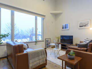 Cozy living room with large windows offering scenic views, leather sofas, and modern decor.
