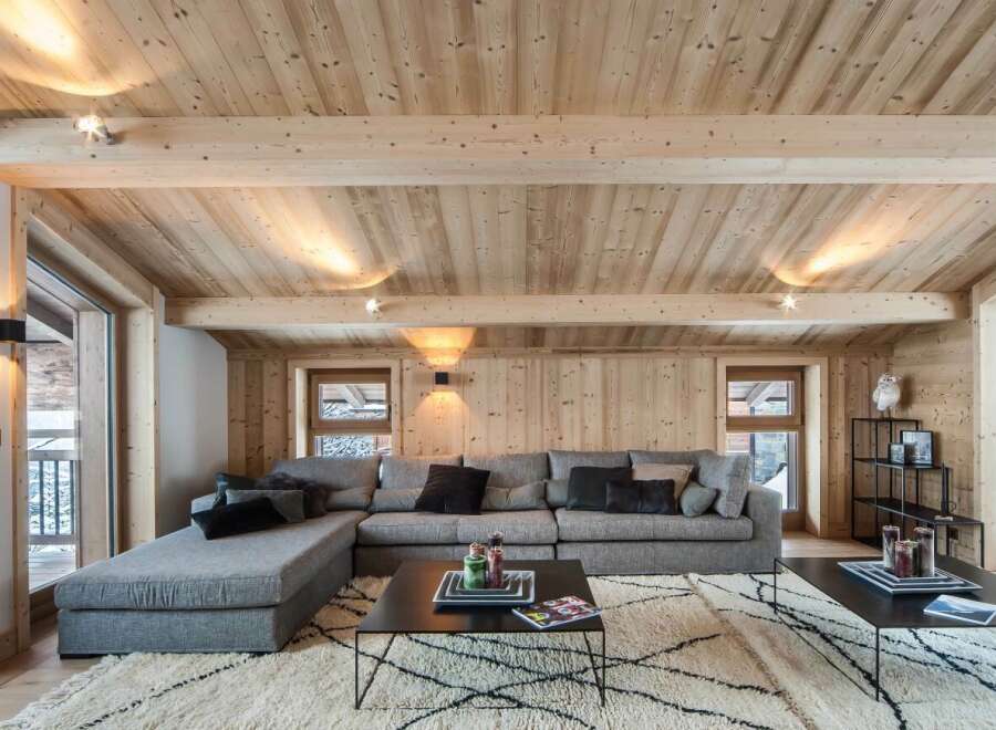 This stunning chalet boasts a spacious living area with a cozy sectional sofa, perfect for relaxing after a day on the slopes.