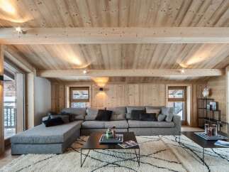 This stunning chalet boasts a spacious living area with a cozy sectional sofa, perfect for relaxing after a day on the slopes.
