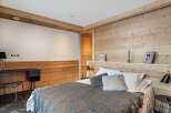This stunning bedroom boasts a cozy and sophisticated design, featuring wood paneling and a plush gray throw blanket.