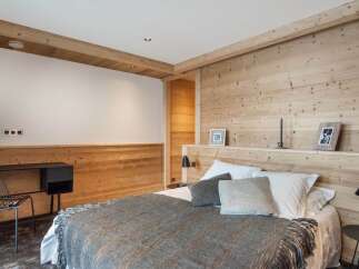 This stunning bedroom boasts a cozy and sophisticated design, featuring wood paneling and a plush gray throw blanket.