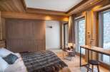 This stunning bedroom boasts a cozy and luxurious design, featuring a comfortable bed with a plush throw, a stylish cowhide chair, and a sleek wooden desk.