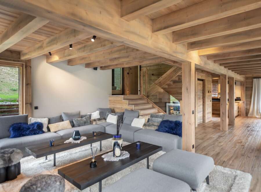 This stunning chalet boasts a spacious open-plan living area with a cozy sectional sofa and plush cushions, perfect for relaxing after a day on the slopes.
