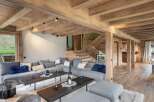 This stunning chalet boasts a spacious open-plan living area with a cozy sectional sofa and plush cushions, perfect for relaxing after a day on the slopes.