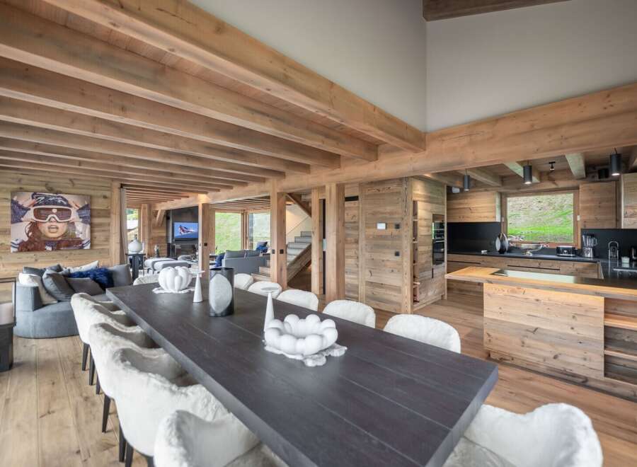 This stunning chalet boasts a spacious open-plan living area with a large dining table perfect for gatherings, a cozy living room with a fireplace, and a fully equipped modern kitchen.
