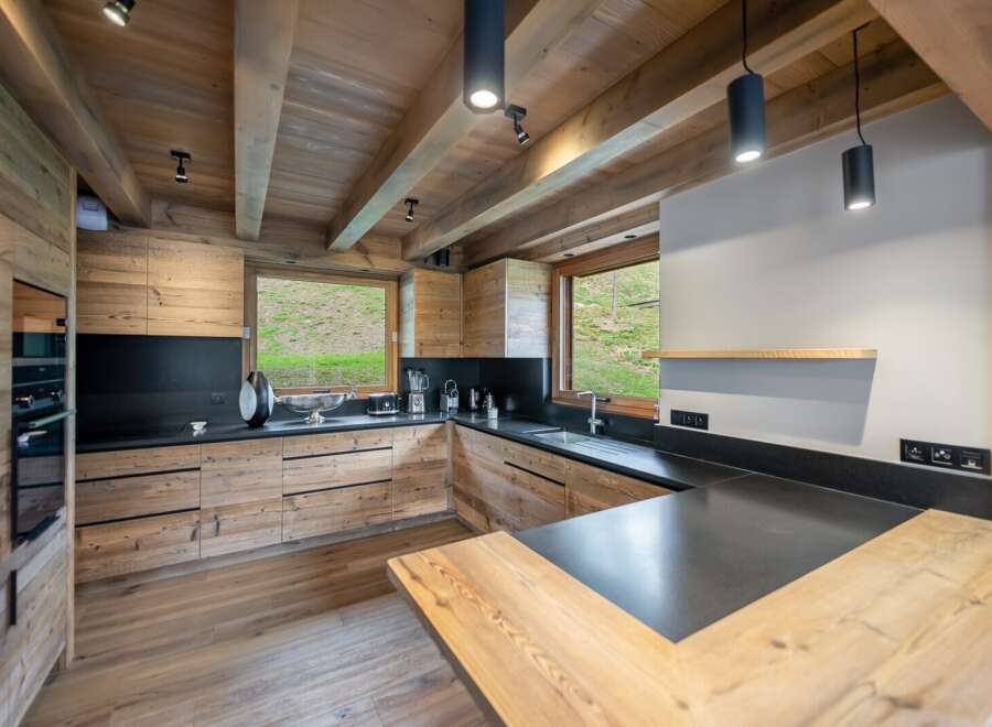 This stunning kitchen boasts a rustic-chic design with exposed wooden beams and a modern black countertop.