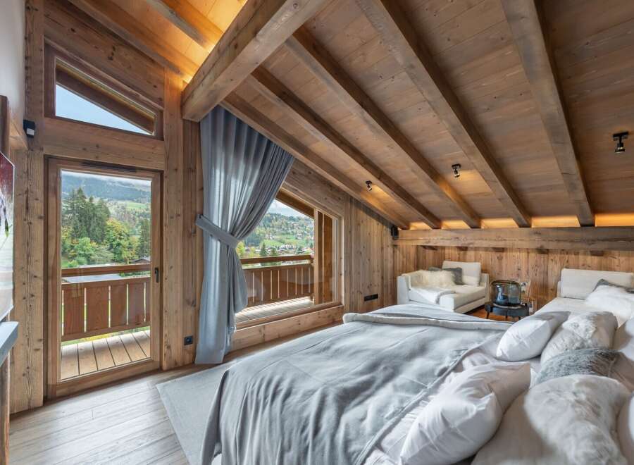 Luxury chalet bedroom with stunning mountain views and exposed wooden beams.