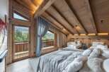 Luxury chalet bedroom with stunning mountain views and exposed wooden beams.