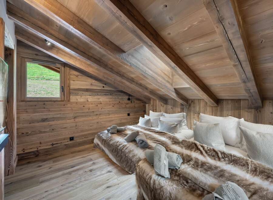 This stunning chalet boasts a spacious attic bedroom with exposed wooden beams and a cozy, rustic atmosphere.