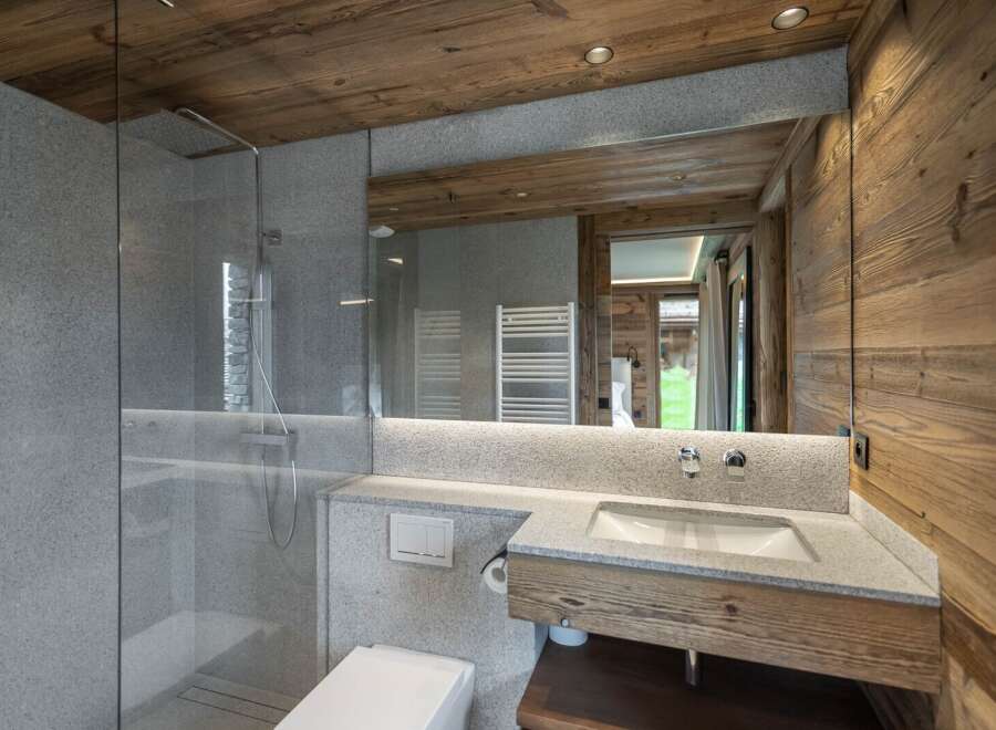 This stunning bathroom boasts a spacious walk-in shower with modern fixtures and a sleek granite countertop vanity.