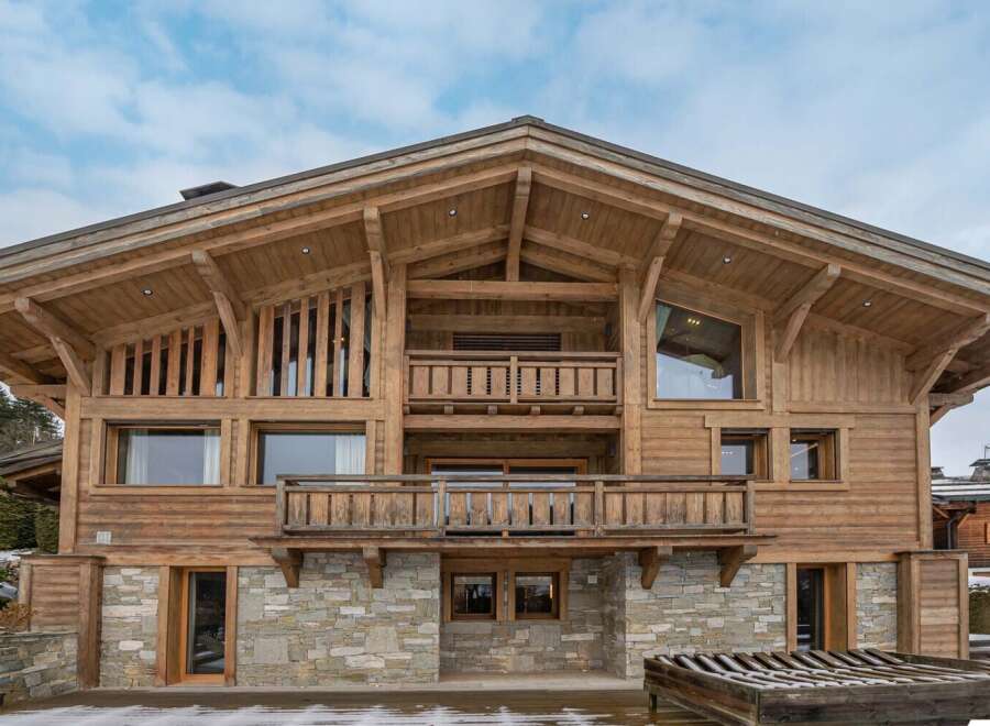 This stunning chalet boasts a beautiful wooden exterior, expansive balconies, and large windows offering breathtaking views.