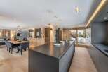 This stunning chalet boasts a spacious open-plan living area with a sleek, modern kitchen featuring a large island and high-end appliances.