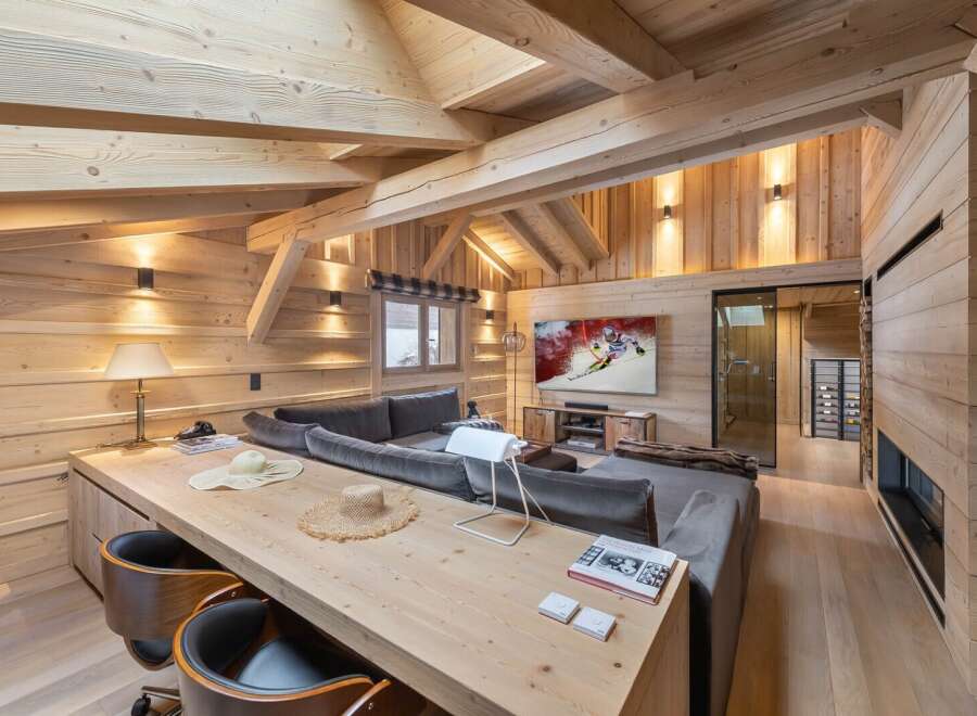 This stunning chalet boasts a spacious open-plan living area with exposed wooden beams and a cozy fireplace.