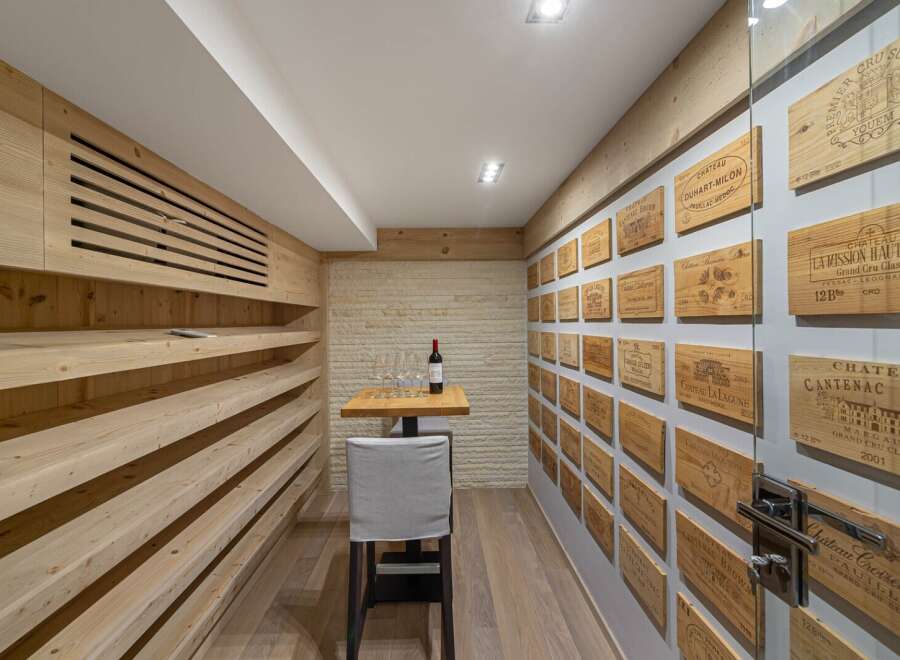 This stunning wine cellar boasts a unique design, featuring wooden shelves and walls adorned with vintage wine crate labels.