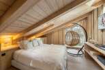 Cozy chalet bedroom with a king-size bed, wooden beams, and a window seat offering stunning views.