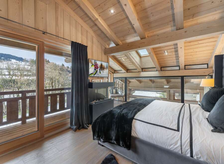 Luxurious chalet bedroom with stunning mountain views and a cozy fireplace.
