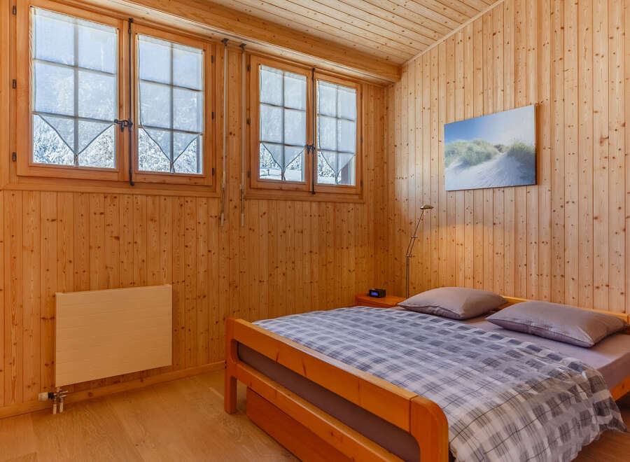 Cozy bedroom with wooden paneling and a comfortable bed.