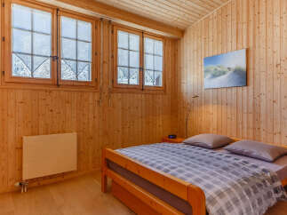 Cozy bedroom with wooden paneling and a comfortable bed.