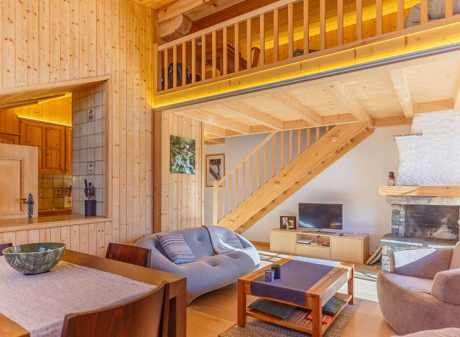 Experience the warmth of this stunning wooden cabin, featuring a cozy living area with a fireplace and a modern kitchen.