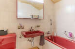 This charming bathroom features a vibrant red sink and bathtub, adding a pop of color to the space.