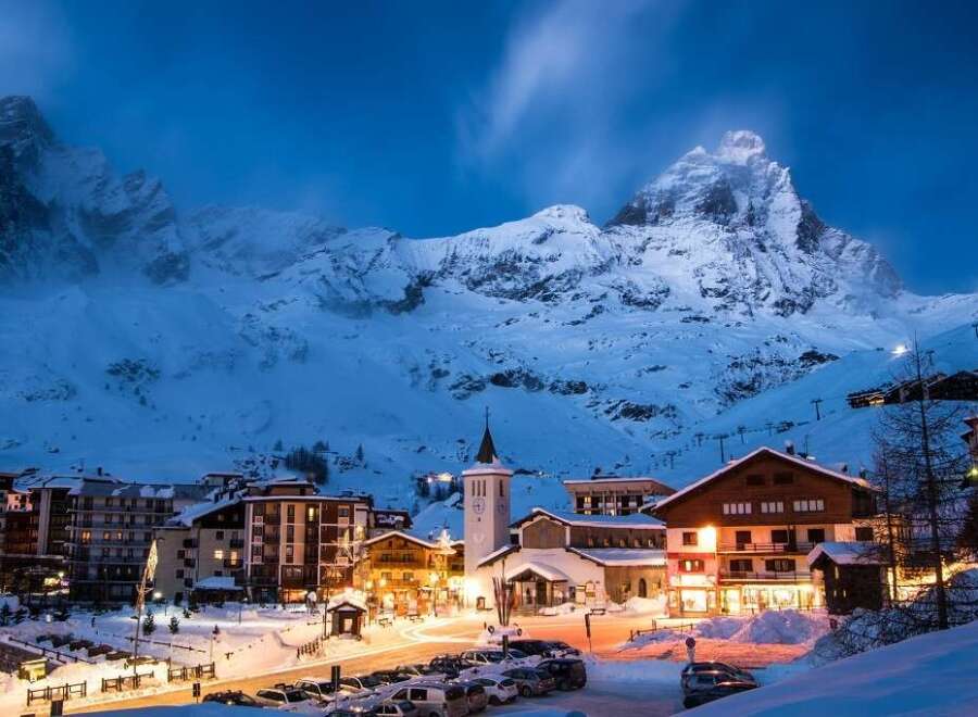 Experience the magic of a snow-covered village nestled at the foot of majestic mountains.