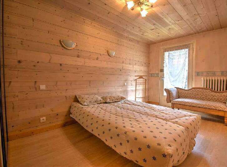 Cozy wooden bedroom with a comfortable double bed and a charming antique settee.