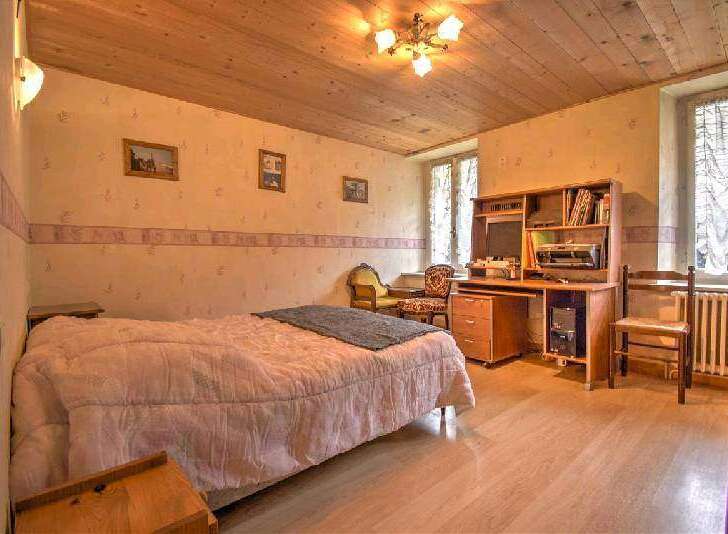 Charming bedroom with wooden ceiling and hardwood floors.