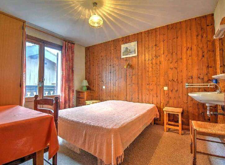 Cozy chalet room with wooden walls and a comfortable double bed.