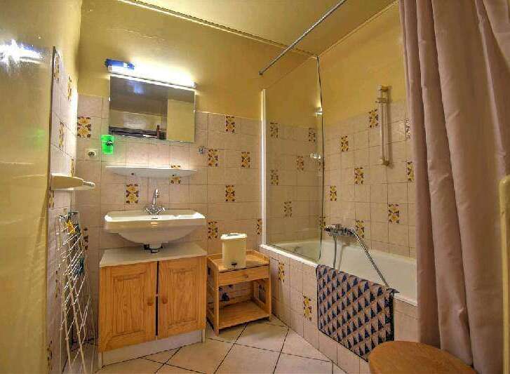 This charming bathroom features a classic tiled shower/tub combination, a wooden vanity with ample storage, and a light and airy atmosphere.