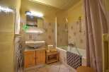 This charming bathroom features a classic tiled shower/tub combination, a wooden vanity with ample storage, and a light and airy atmosphere.