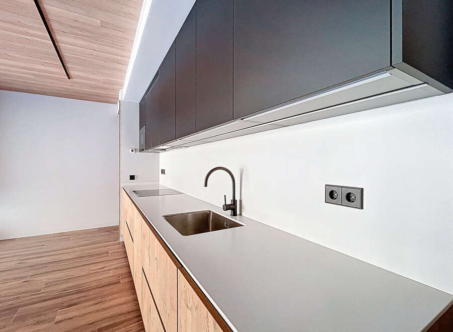 This modern kitchen boasts sleek, dark cabinetry and a pristine white countertop, creating a sophisticated and functional space.