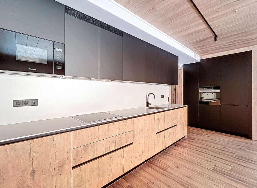 This modern kitchen boasts sleek, dark cabinetry and a minimalist design.