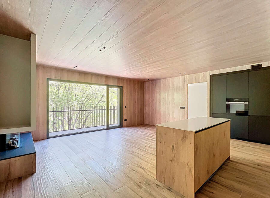 Stunning open-plan living space with large windows offering abundant natural light and views of lush greenery.