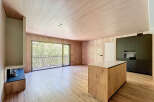 Stunning open-plan living space with large windows offering abundant natural light and views of lush greenery.