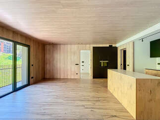 Stunning open-plan living space with wood flooring and walls, creating a warm and inviting atmosphere.