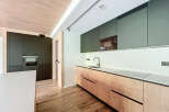Modern kitchen with sleek dark green upper cabinets and light wood lower cabinets.