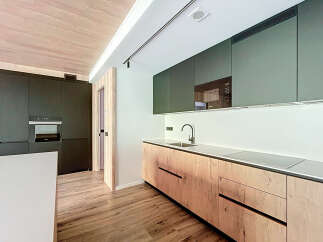 Modern kitchen with sleek dark green upper cabinets and light wood lower cabinets.