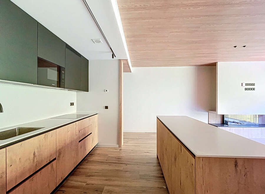 Modern kitchen with sleek dark green upper cabinets and light wood lower cabinets.