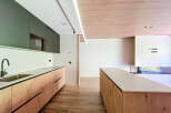 Modern kitchen with sleek dark green upper cabinets and light wood lower cabinets.
