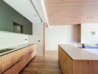 Modern kitchen with sleek dark green upper cabinets and light wood lower cabinets.