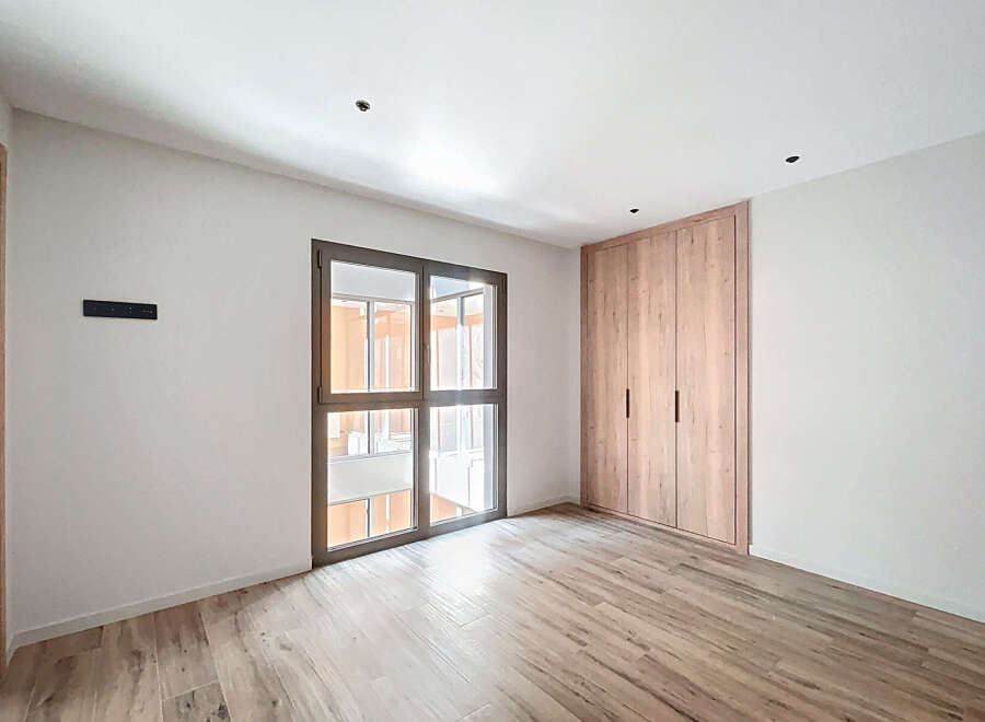 This stunning property boasts a spacious bedroom with ample natural light from a large window.