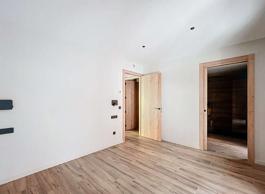 This stunning property boasts a spacious, bright interior with sleek wooden flooring and modern light fixtures.