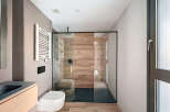 Modern bathroom with a sleek glass shower enclosure and wooden wall tiles.