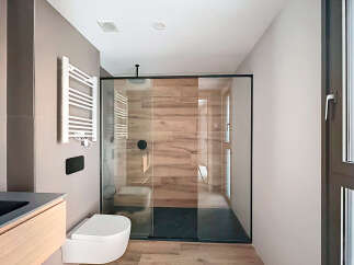 Modern bathroom with a sleek glass shower enclosure and wooden wall tiles.