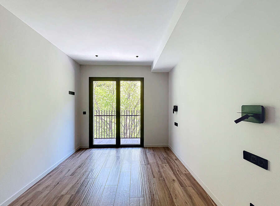 This stunning property boasts a spacious, bright room with large glass doors leading to a private balcony, perfect for enjoying the outdoors.