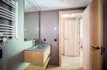 Modern bathroom with sleek gray sink and wooden vanity, complemented by a heated towel rack and stylish light wood doors.