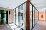 Modern hallway with floor-to-ceiling glass walls offering abundant natural light and views of the inner courtyard.